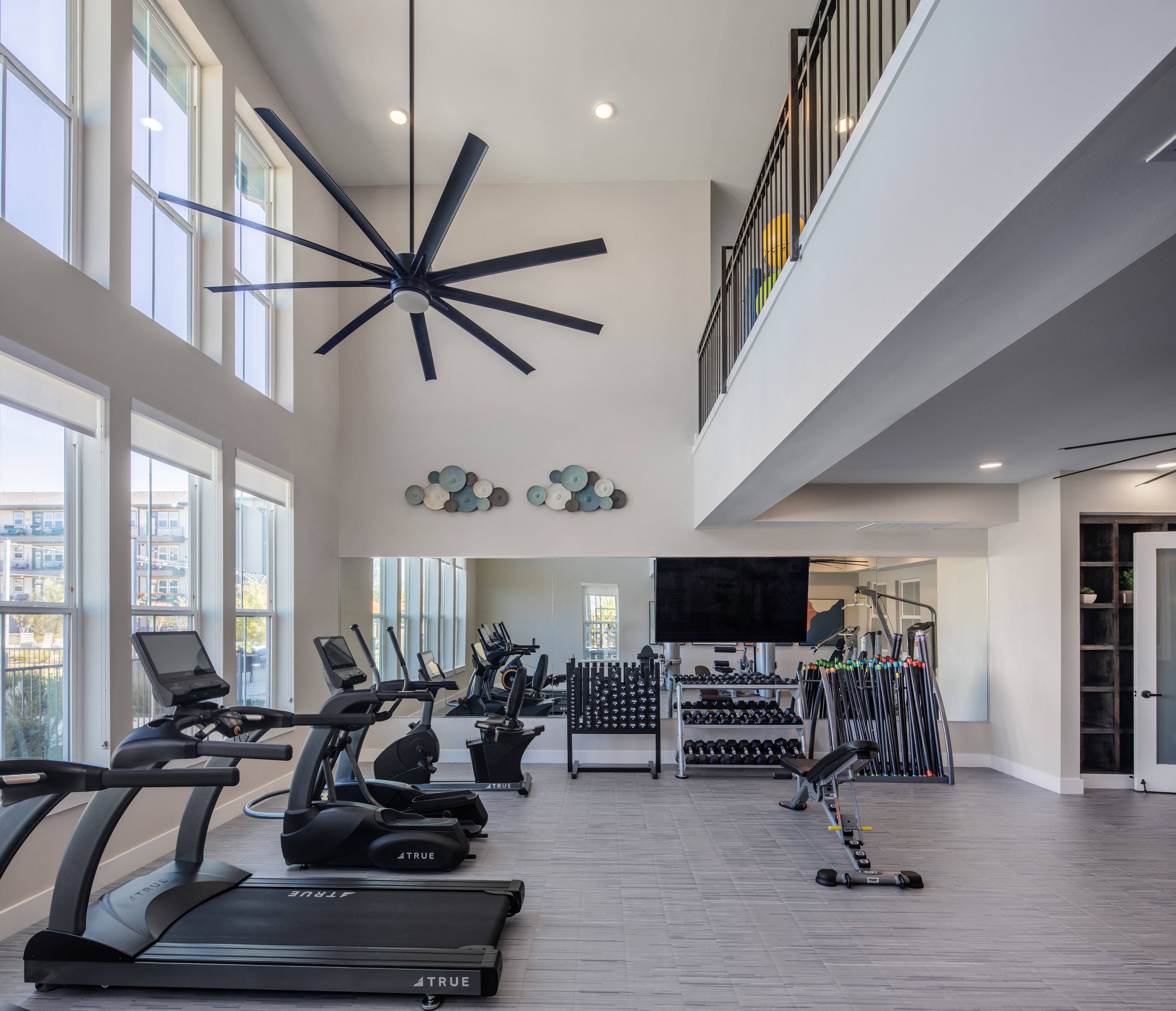 a gym with treadmills and weights and a tv